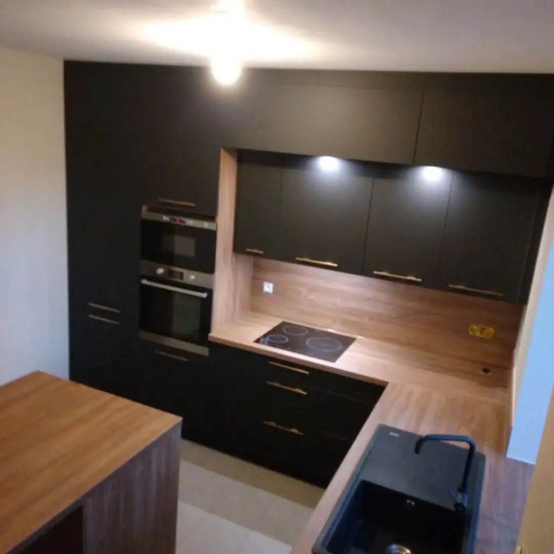 Cuisine moderne avec électroménager encastré et crédence bois — posée par Agencement Lennon, Landivisiau.